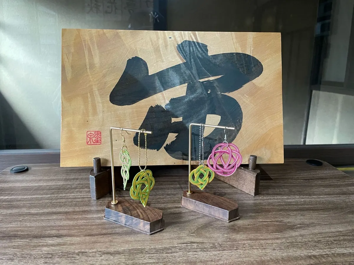 Mizuhiki cord earrings in front of a calligraphy board